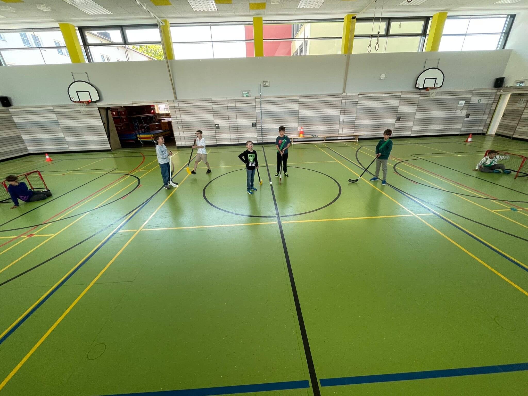 Kinder in der Turnhalle beim Hockey spielen