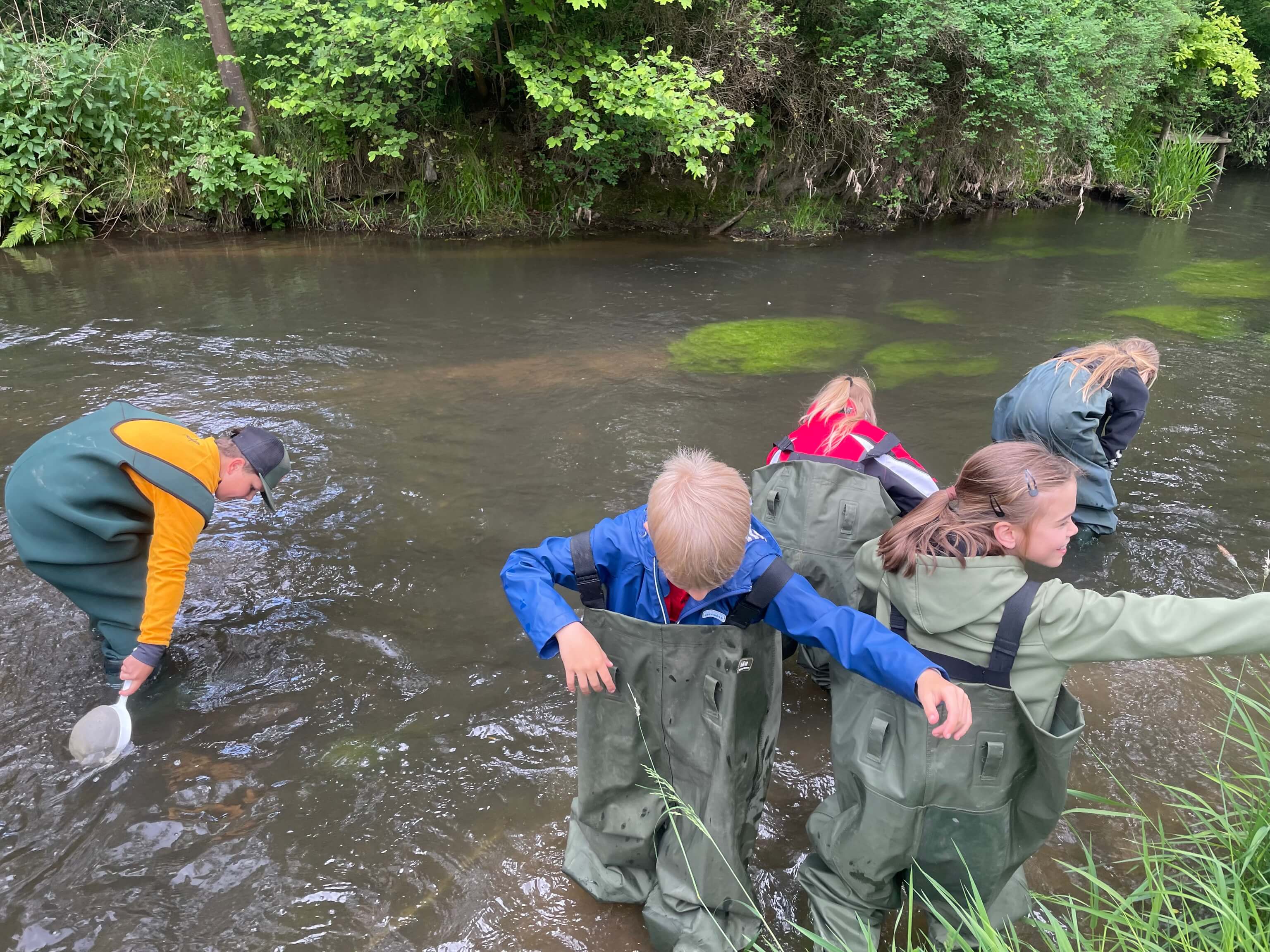 Kinder fischen mit Watthosen im Fluss