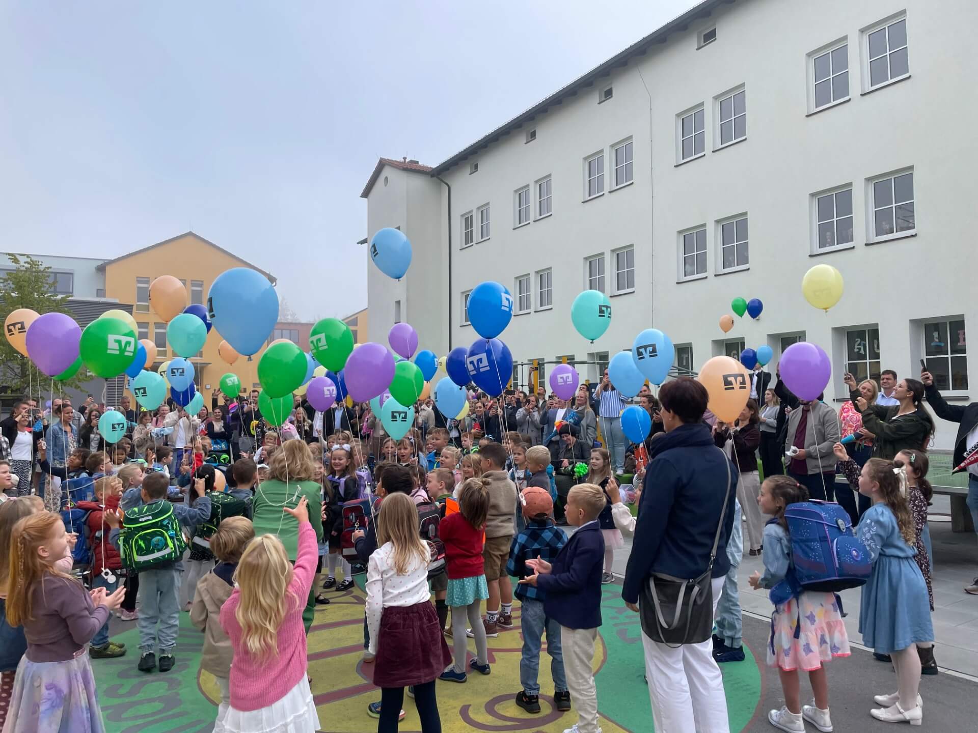 Kinder halten Luftballons fest , alle stehen auf dem Pausenhof