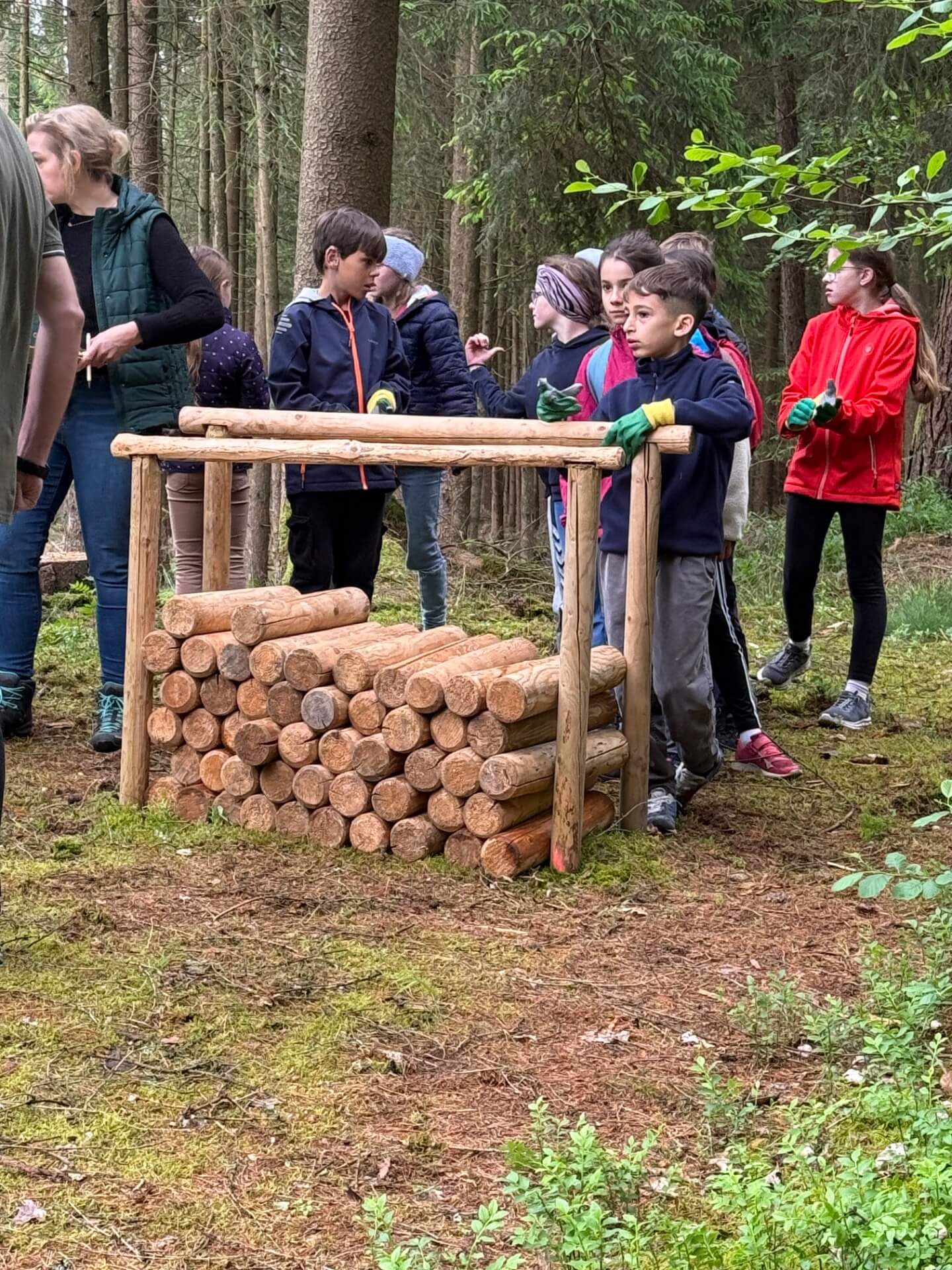 Kinder stehen hinter Holzstapel